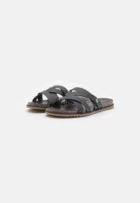 Black slide sandals with multiple crossed straps, a textured footbed, and a brown rubber outsole featuring a wavy tread pattern.