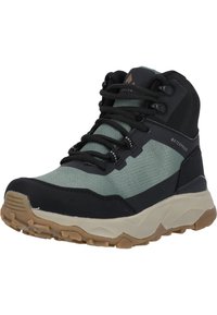 Bottes de randonnée imperméables montantes avec une tige en mesh vert foncé, des accents noirs et une semelle en caoutchouc beige avec un motif de crampons pour l'adhérence.