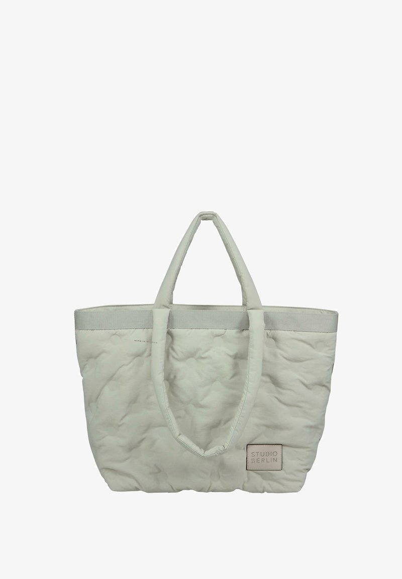 Quilted tote bag i lysegrå med solide håndtag, en tekstureret overflade og et rektangulært logo-mærke, der siger "STUDIO BERLIN."
