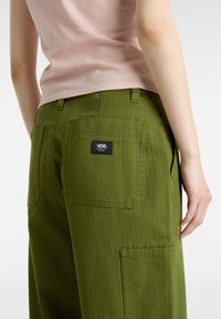 Gröna cargobyxor i kraftig bomull, med flera fickor, rak passform och en svart VANS-etikett på bakfickan.