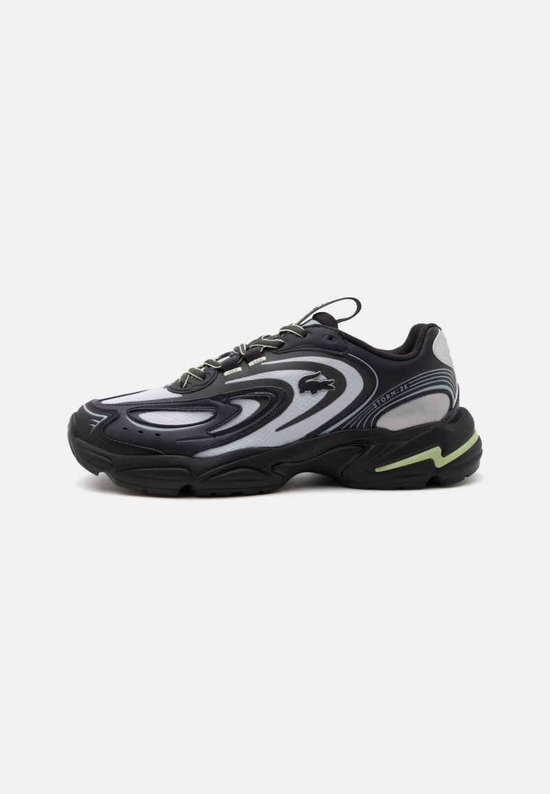 Μαύρο και γκρι sneaker Lacoste Storm 2K με κυματιστά σχέδια, σχεδιασμό με κορδόνια και παχύ πάτο με φωτεινή πράσινη λεπτομέρεια.