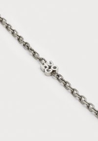 Bracciale in metallo a catena con un design a maglia alternato in tonalità argento; presenta un ciondolo centrale in argento con la scritta "Hugo".
