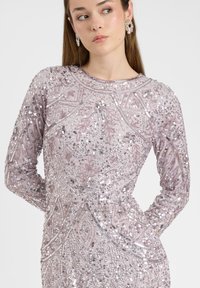 Langarmkleid in hellem Lavendel, verziert mit Pailletten und aufwändiger Perlenstickerei. Mit rundem Ausschnitt und figurbetonter Silhouette.