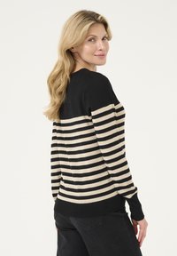 Pull rayé noir et beige à manches longues et col rond. Texture douce, poignets et ourlet côtelés contrastants. Vue arrière affichée.
