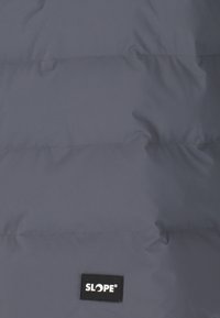 Pufferjakke i mørkegrå nylon med vandret syninger og et sort "SLOPE" logo label nederst.