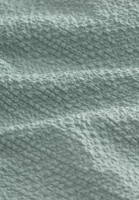 Tessuto strutturato in un blu-turchese chiaro, caratterizzato da un motivo tessuto con forme a diamante sollevate, che conferisce una finitura morbida e tattile.