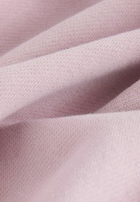 Tissu violet clair et doux avec une texture en maille fine, présenté en gros plan avec des plis mettant en valeur la douceur et les détails subtils des coutures.