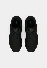 Black athletic shoes with a textured knit upper, round laces, and branding on the tongue; rubber sole with a cushioned insole.