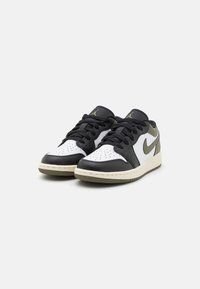 Svarta och vita lädersneakers med en texturerad yta, med en grön accent på sidan, rund tå och platta snören.