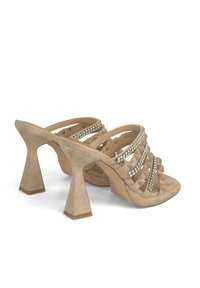 Le sandali con tacco in suede beige presentano molteplici cinturini incrociati decorati con piccole strass, un ampio tacco a blocco e una soletta imbottita.