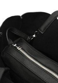 Zwarte handtas met een mix van leer en stof aan de binnenkant, voorzien van een ritscompartiment en een gladde textuur. Accenten van zilverkleurig beslag.