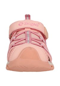 Pink sports shoe with mesh upper, elastic laces, Velcro strap, and textured rubber sole. Features zigzag branding on the strap.