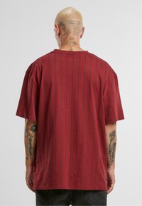 Rødstribet T-shirt i blødt stof. Har korte ærmer, en afslappet pasform og en rund halsudskæring. Synlig tatoveringsdetalje på underarmen.