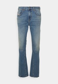 Jeans acampanados de color azul, confeccionados en denim, con una cintura de altura media, cinco bolsillos y un ligero desgaste en los muslos. Se aprecian detalles de costura expuesta.
