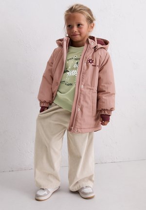 Pink padded jacket with a hood and elastic cuffs, layered over a light green graphic sweatshirt. Cream corduroy wide-leg pants and sneakers.
