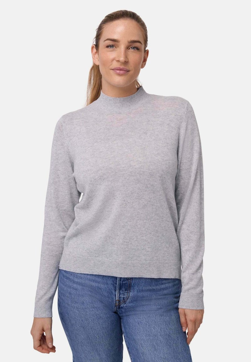 Lichtgrijze longsleeve trui met een hoge kraag, gemaakt van zachte stof, met ribgebreide boorden en zoom, gedragen met blauwe jeans.