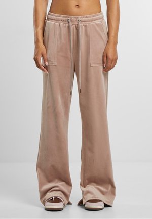 Béžové široké kalhoty s předními našitými kapsami a pasem na šňůrku, nošené s odpovídajícími béžovými nazouvacími botami.