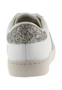 Sneaker bianca con un tacco accentuato da glitter argento metallico testurizzato e suola in gomma beige. Materiale superiore liscio con dettagli di cucitura minimi.