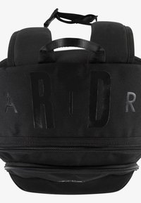 Fekete hátizsák texturált anyagból, feltűnő logóval, két párnázott vállpánttal és az alján cipzáras rekesszel.