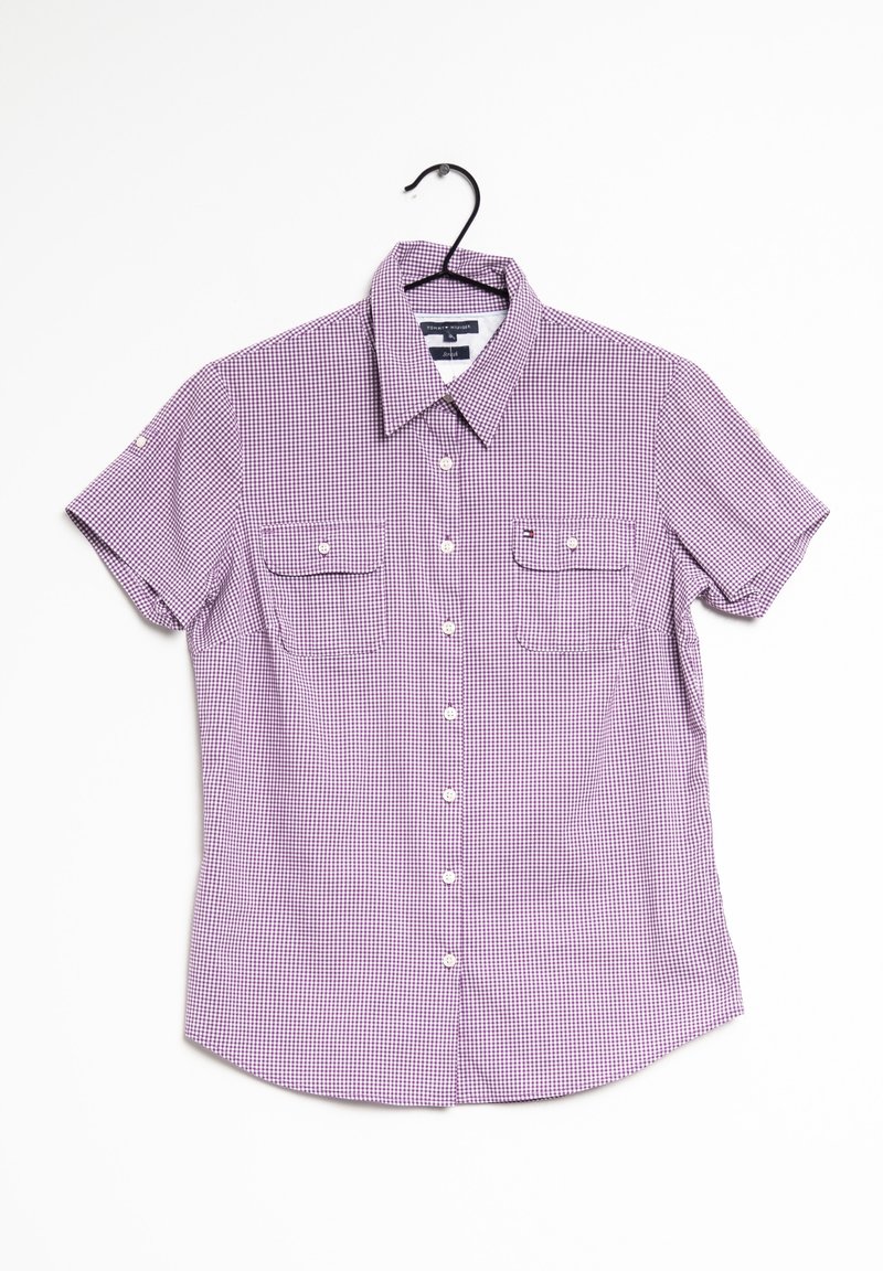Camicia a maniche corte a righe viola e bianche con due tasche sul petto, appesa a una gruccia nera su uno sfondo bianco.