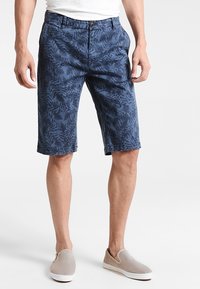 Marinblå shorts med ett mönster av ormbunksblad, tillverkade av lätt tyg. Utrustade med knappstängning och bälteshällor, som slutar strax över knäet.