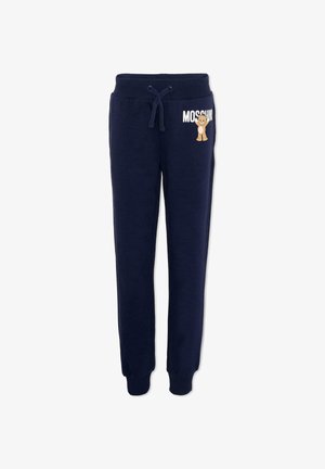 Pantalon de jogging bleu marine avec ceinture et poignets côtelés, cordon de serrage, texte blanc "Moschino" et petit dessin d'ourson sur la hanche gauche.