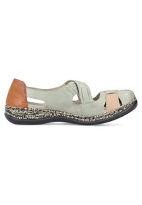 Chaussure en cuir vert clair avec découpes, accents beige et semelle noire texturée. Possède une large sangle et un design flexible.