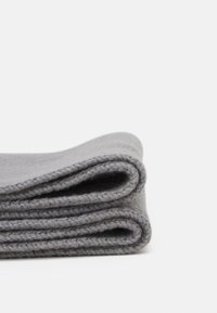 Couverture grise pliée avec une texture douce, présentant un design tricoté simple et des coutures de contraste.