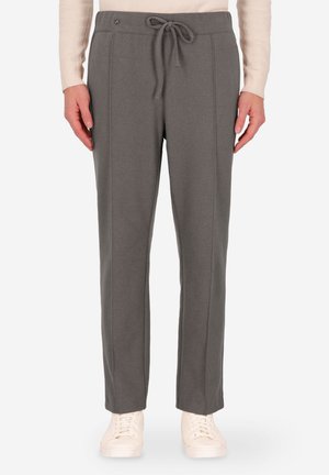 Pantaloni della tuta grigi realizzati in tessuto morbido, con vita regolabile e cuciture laterali, dal taglio rilassato. Abbinate a sneakers bianche.
