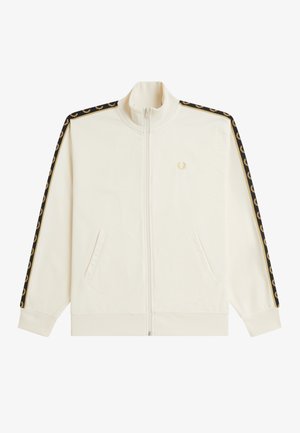 Veste de survêtement crème zippée avec une bande laurier noire et dorée sur les manches et un petit logo de couronne de laurier dorée sur la poitrine.