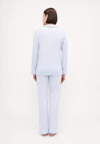 Ljusblå pyjamas med långärmad topp med krage och matchande byxor. Mjuk tyg, enkel design och manschetter vid anklarna.