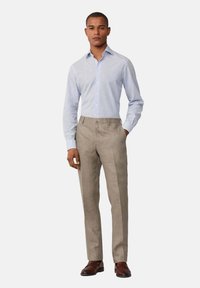Hellblau-weiß gestreifte Button-Up-Bluse kombiniert mit hellbeigen Leinenhosen. Glatte Textur, taillierte Passform und braune Anzugschuhe.