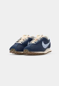 Sneakeri tamnoplave boje s teksturiranom gornjom tkaninom, svijetloplavi Swoosh, bež potplat i kakao žice. Čvrsta gumena podloga za prianjanje.