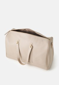 Beige leather duffel bag with a textured finish, gold-tone hardware, zip closure, and dual handles for carrying.