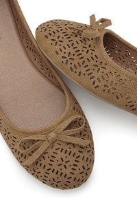 Braune Wildleder-Balletschuhe mit durchbrochenen Designs, einer abgerundeten Spitze und einem kleinen Schleifenakzent an der Vorderseite. Die strukturierte Innensohle ist sichtbar.