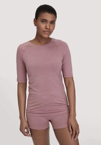 Lichtroze sporttop met halve mouwen, voorzien van een ronde halslijn en gemaakt van soepele, ademende stof, gecombineerd met bijpassende shorts.