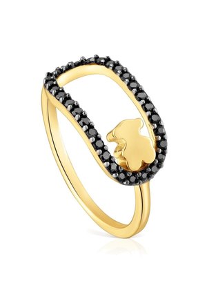 Anello d'oro con cima ovale aperta bordata da piccole pietre nere e una piccola forma a orsetto d'oro all'interno dell'ovale.