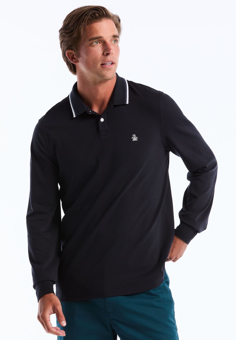 Polo à manches longues navy avec des rayures blanches au col, arborant un petit logo sur la poitrine et une coupe classique. Fabriqué dans un matériau lisse et léger.