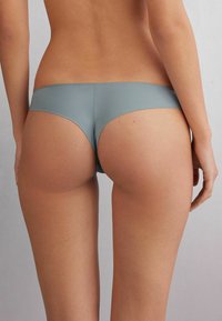 Zachte grijze naadloze bikini slips met een gladde textuur, lage taille en minimalistische snit, die een moderne silhouet benadrukken.