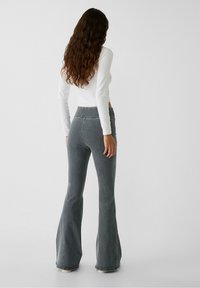 Grijze flared jeans met een hoge taille, gemaakt van denim, met een gladde textuur en gestikte details langs de naden en boorden.