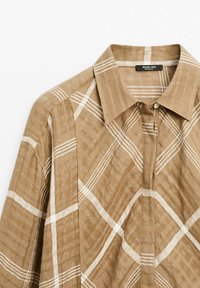 Bruin geruit shirt van textiel met een textuur, uitgerust met een knop-om-knop kraag, witte horizontale en verticale strepen, en een comfortabele pasvorm.