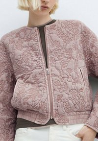 Giacca bomber trapuntata in rosa pallido, con ricami floreali, chiusura a zip, polsini a costine e scollatura tonda. Tessuto morbido e strutturato.