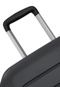 Poignée de valise noire étendue avec deux tiges télescopiques métalliques argentées sur fond blanc.
