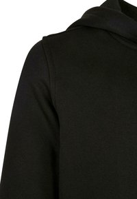 Juodas gobtuvas su grioveliu, laisvo kirpimo ir klasikinio dizaino. Turi gobtuvą ir pečių siūles, nematomų akcentų.