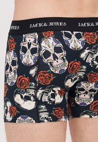 Herren Boxershorts aus elastischem schwarzem Stoff mit einem bunten Totenkopf- und Rosenmotiv, ausgestattet mit einem einfarbigen schwarzen Bund, der mit "JACK & JONES" beschriftet ist.