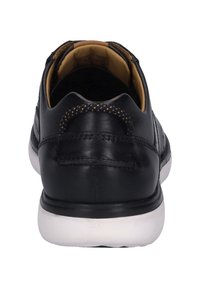 Czarne skórzane sneakersy o gładkiej fakturze, kontrastująca biała podeszwa oraz dekoracyjne szwy na pięcie. Minimalistyczny design bez widocznych logo.