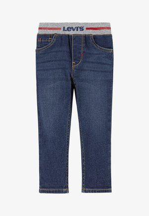 Jean en denim bleu foncé avec une ceinture élastique grise présentant un motif rayé rouge et bleu. Cinq poches et détails de couture jaune.