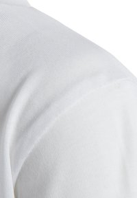 Tela de camisa de algodón blanco, con una textura suave y un ligero canalé, que presenta una caída suave en la zona de los hombros.