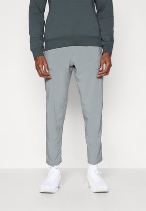 Lys grå, letvægts, tapered bukser med sidelommer; parret med hvide træningssko og en mørkegrøn sweatshirt.