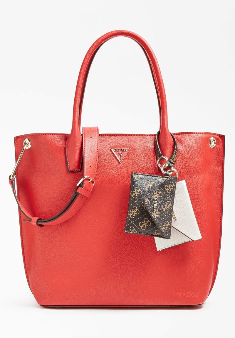 Rød læder tote taske med dual håndtag og justerbar rem, der har en lille sort-hvid mønstret plysse fastgjort foran.